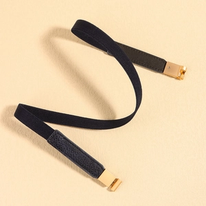 Detail of black elastic skinny belt featuring light gold buckle and lychee leather ends