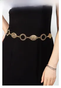Detail of vintage gold metal waist chain with embossed relief charms on a black dress