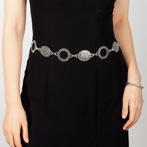 Detail of vintage silver metal waist chain with intricate hollow patterns on a black dress