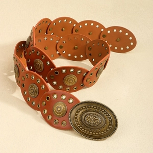 Detail of bohemian leather belt featuring floral embossed metal buckles and studs