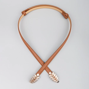 Close-up of brown faux leather waist belt with golden leaf-shaped metal buckle design