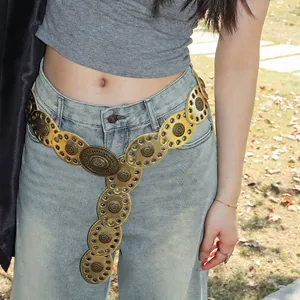 Detail of bohemian gold metal waist chain with sun flower relief pattern on denim