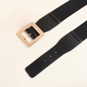 Détail d'une large ceinture élastique noire avec une boucle carrée en métal doré poli