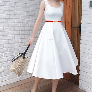 Detail shot of a slim red leather belt featuring a golden leaf buckle on a white dress