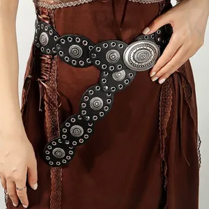 Detail of Bohemian black leather belt with silver engraved metal discs on a lace dress