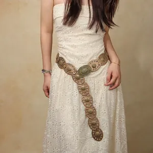 Detail of bohemian leather belt with antique bronze buckle over a white lace dress