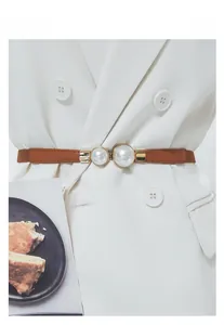 Detail view of brown leather skinny belt with double pearl accents on gold buckle