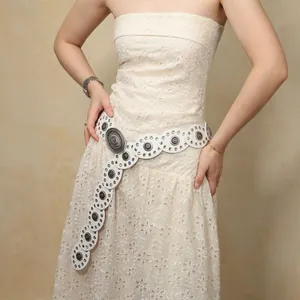 Close-up of a white bohemian hollowed-out waist belt with silver metal buckles on a dress