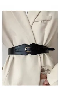 Detail of wide black elastic waist belt with gold buckle styled over an ivory blazer