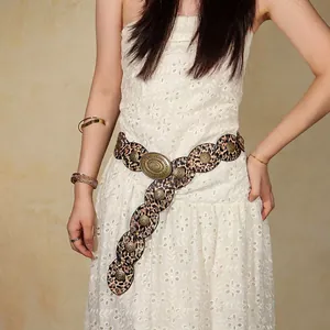 Close-up of leopard print belt with vintage bronze rivets on a white lace dress