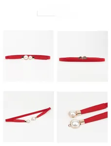 Detail view of red elastic skinny belt featuring elegant pearl and gold buckle decoration