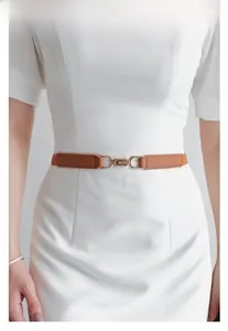 Detail of slim brown leather belt with gold U-shape buckle on a white dress