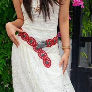 Detail of red Bohemian leather belt with vintage silver buckle on white lace skirt