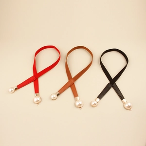Close-up of three elastic skinny belts in red, black and brown with elegant pearl buckle