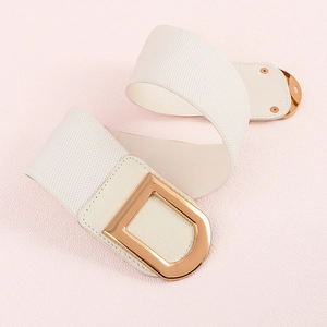 Détail d'une ceinture élastique beige avec une boucle métallique dorée en forme de D