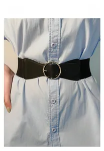 Detail of black wide elastic waist belt with silver round buckle on a blue shirt