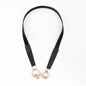 Detail of slim elastic waist belt featuring cream faux pearls and gold metal base