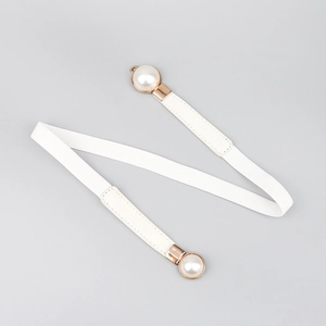 Detail of white elastic waist belt with rose gold pearl buckle and leather trim