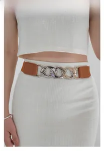 Détail d'une ceinture élastique marron avec une grosse boucle de chaîne en métal argenté