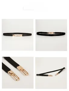 Detail of minimalist black leather skinny belt featuring a golden metallic buckle closure