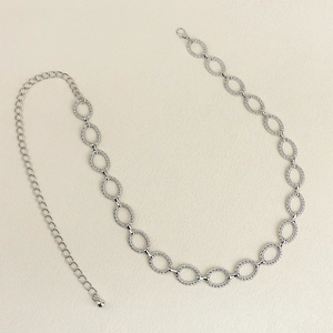 Détail d'une chaîne de taille en métal argenté avec anneaux spirale et fermoir ajustable