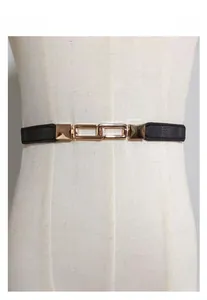 Detail of minimalist black thin waist belt with golden interlocking rectangle buckle