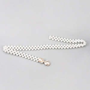 Détail d'une ceinture en perles avec boucle dorée en forme de nœud et cristaux