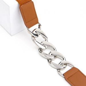 Détail d'une ceinture élastique marron avec de grosses chaînes en métal argenté et cuir