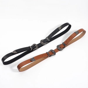 Détail de boucles de ceinture western avec gravures florales argentées en noir et marron