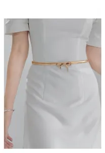 Detailed close-up of a stylish gold metal bow tie elastic waist chain for women fashion