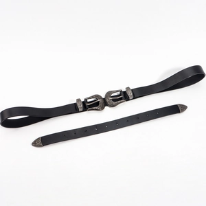 Détail des doubles boucles vintage argentées gravées sur une ceinture en cuir noir