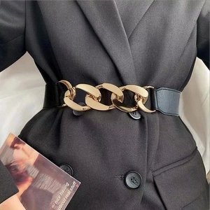 Ceinture femme extensible en cuir avec grosse boucle chaîne dorée sur un blazer noir
