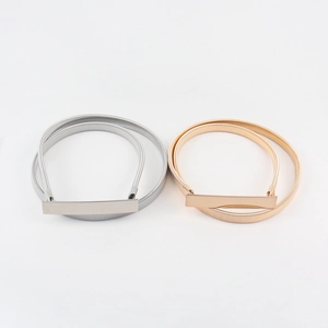 Detail of elegant gold and silver elastic metal spring belts with polished rectangular buckles