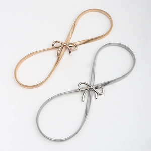 Detail of gold and silver elastic bow belts with elegant thin metal chain links
