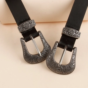 Détails de gravures florales vintage sur la boucle argentée d'une ceinture noire