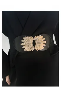 Detail of a wide elastic black waist belt with a golden feather buckle on a blazer