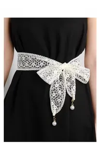 Close-up of white floral lace belt with elegant bow and hanging pearl pendants