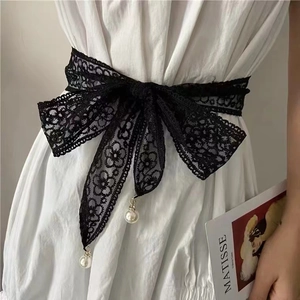 Close-up of black floral lace waist belt featuring delicate white pearl pendant accents