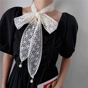 Close-up of white floral lace bow belt with elegant pearl pendants on a black dress