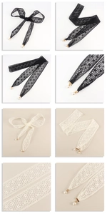 Close-up of lace ribbon waist belt with floral patterns and pearl tassel pendants