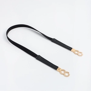Close-up of elastic waist belt with textured gold interlaced metal buckle on black strap