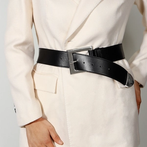 Close-up of black elastic wide waist belt with silver metal buckle on a white blazer