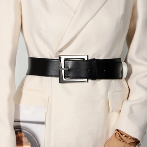 Close-up of a wide black leather belt with a large square silver buckle on a beige blazer