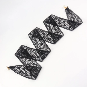 Detail of black lace belt featuring intricate floral patterns and elegant white pearl drops