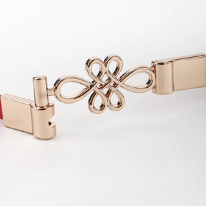 Close-up of a polished gold metallic buckle with decorative interlaced knot design