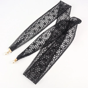 Close-up of black floral lace belt with elegant pearl pendants and golden metal buckles