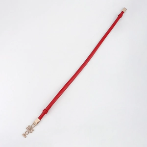 Detail of red thin PU leather belt featuring a decorative gold-toned knot buckle