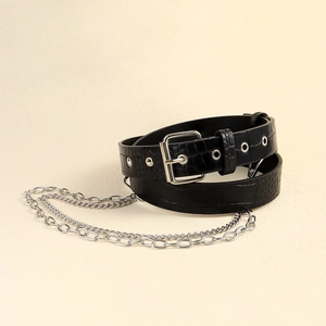 Dettaglio cintura nera stampa coccodrillo con fibbia argentata e catene metalliche stile punk