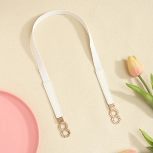 Detail of white elastic waist belt with textured leather ends and gold twisted metal buckle