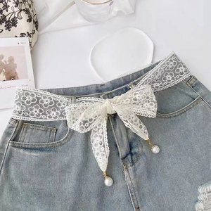 Elegant white lace waist belt with bow knot and pearls styled on blue denim shorts